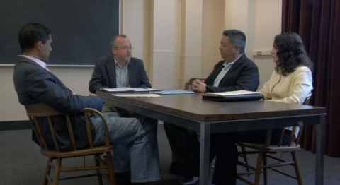 Four people sit around a table in an interview setting